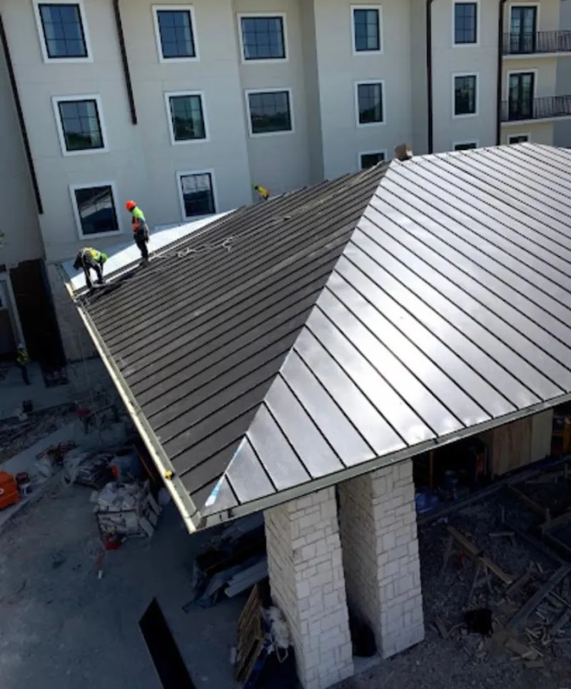 Crew installing standing seam metal roof panels on a commercial project in Clarksville